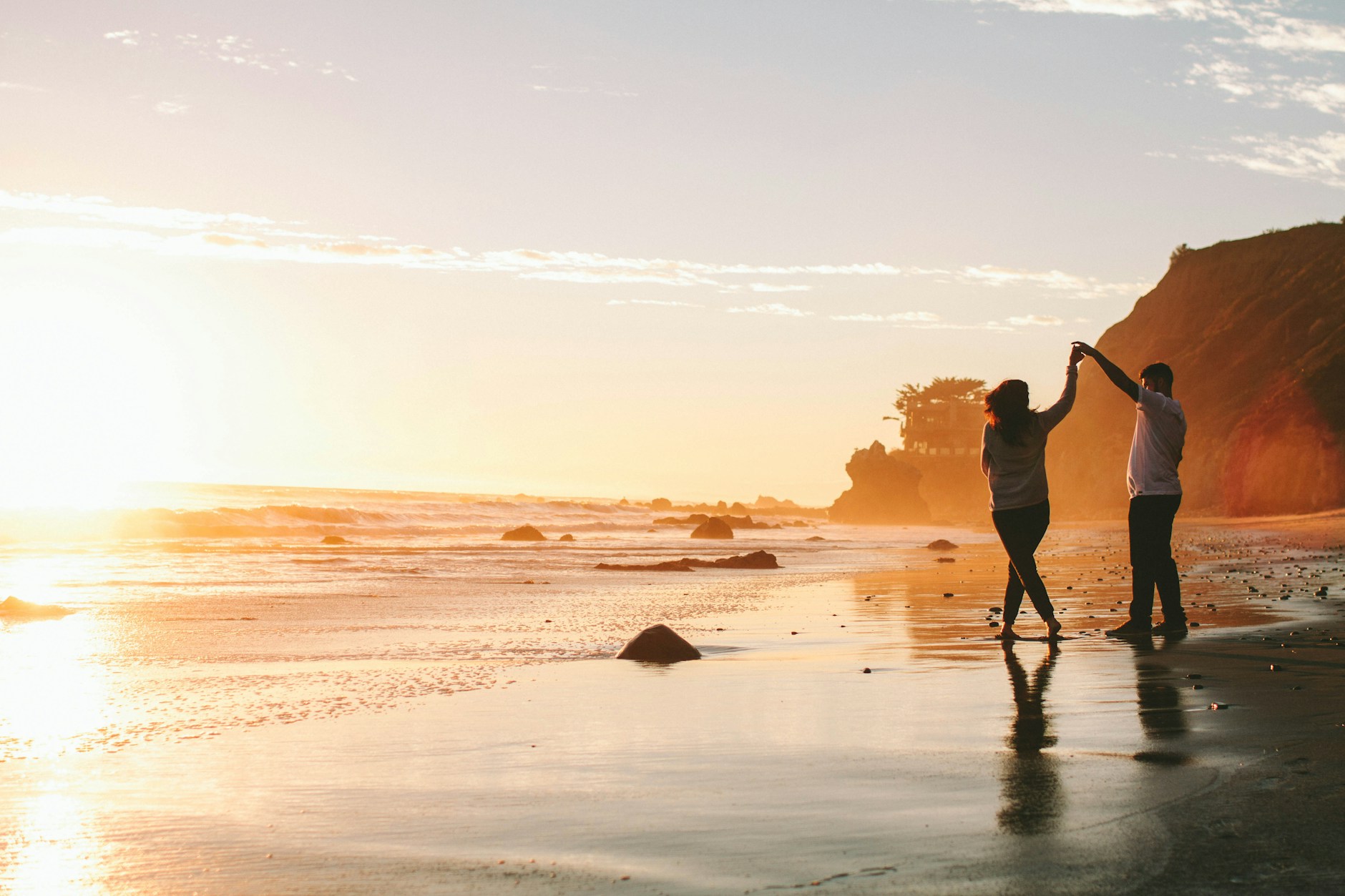A couple dancing on the beach at golden hour